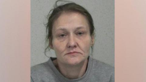 Police custody image of Donna English. She is looking directly into the camera, and has dark hair. She is wearing a grey sweatshirt.