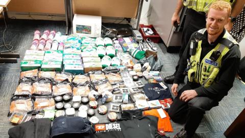 A police officer by a haul of stolen items