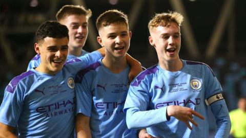 A young Cole Palmer doing a goal celebration with his hand while backed up by three players, including Liam Delap