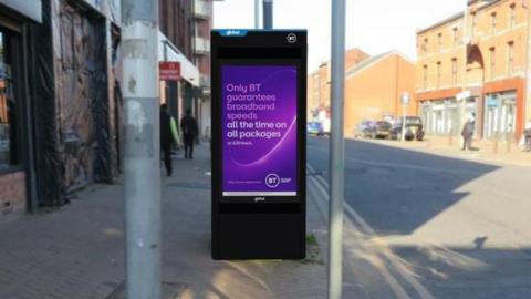 A digitally created image of a tall black technological unit on a footpath. It has a big purple screen on it that reads 'Only BT guarantees broadband speeds". 