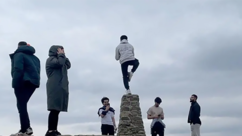 People standing near the Mam Tor trig, with one person standing on top having their photo taken
