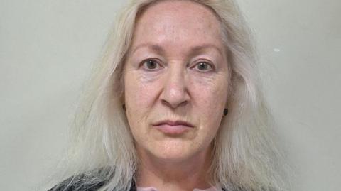 A custody photo of a woman with long grey hair.