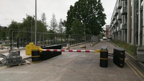 Large black security barriers with a red and white striped pole between them.
