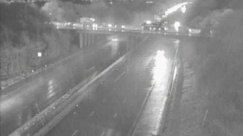 An empty motorway in the dark with car lights and rain. Image from a motorway camera.