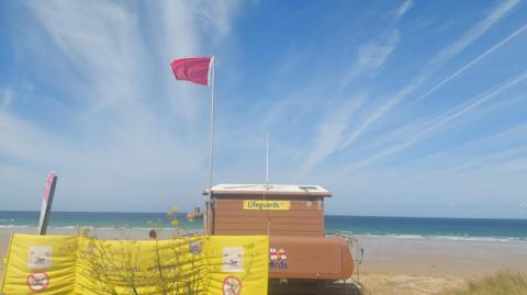 A picture of a beach with a large red flag flying.