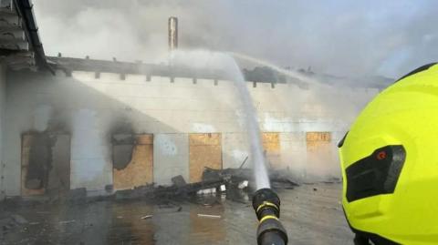 Firehoses being used to dampen down the boarded up stable block at the mansion.