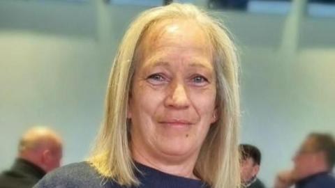 Inverness woman Miriam MacDonald has shoulder length blonde hair and is wearing a blue jumper. She is at a function. There are three men in the background.
