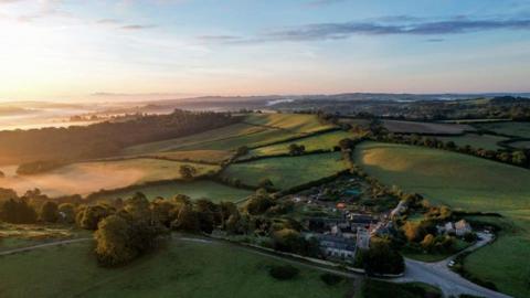 View from the sky over fields at Wolborough Barton with a church in the foreground