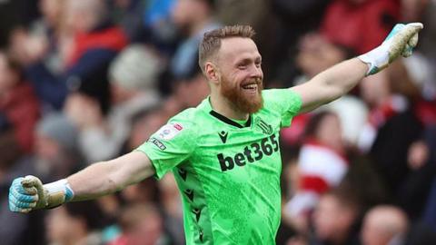 Stoke goalkeeper Viktor Johansson smiles and stretches his arms out in celebration