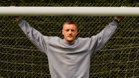 Jamie Vardy stood in a goal with his arms outstretched and holding onto the crossbar