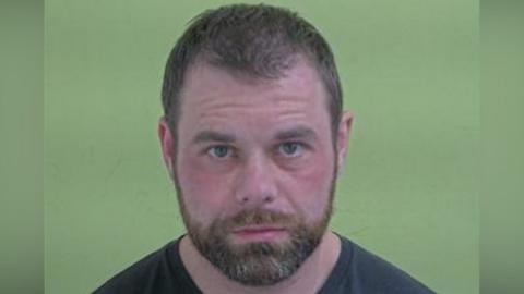 Mugshot of Binding, who has short brown hair and a beard.