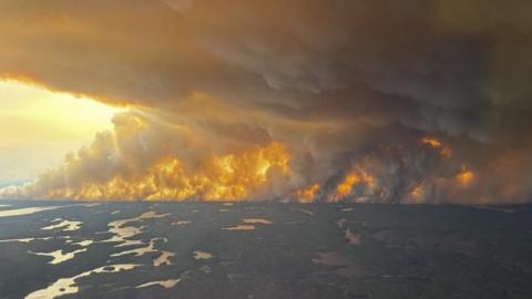 A handout photo made available by the government of Manitoba shows a large wildfire near Flin Flon, Manitoba, Canada. It shows woods and flames with large plumes of smoke filling the sky