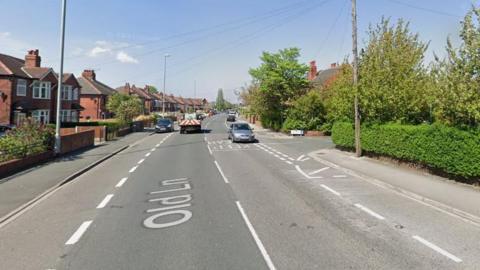 Google Streetview image of Old Lane, Beeston which shows houses on one side of the road and hedges on the otheres bouse