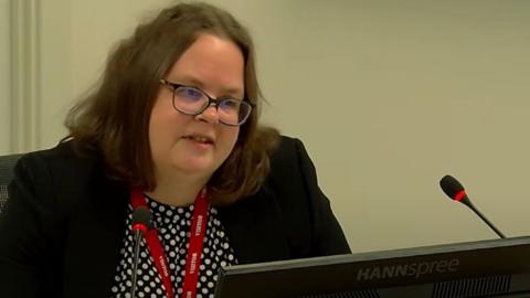 Dr Teresa Inkster sitting in front of a computer monitor, speaking into a microphone