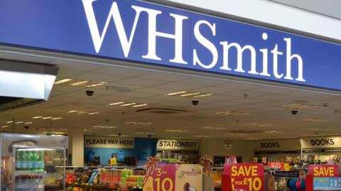 An image of the WHSmith shop front in Jersey airport. You can see the company logo, and below it a range of products. 