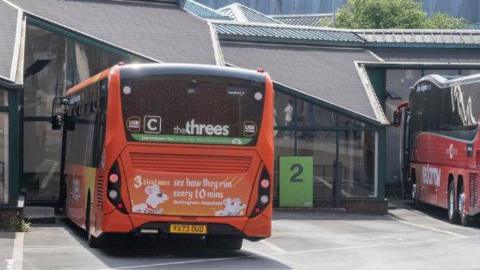 Two buses parked at Victoria Bus Station, a single storey building with glazed walls