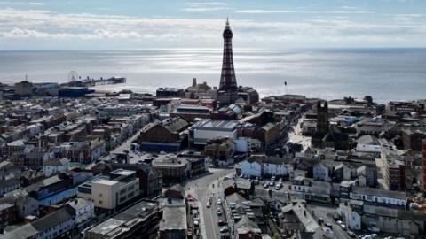 Drone view of Blackpool town with Blackpool Tower and the Irish Sea in the background.