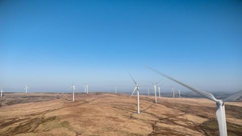 Large white wind turbines can be seen spread across the landscape in this computer generated image.