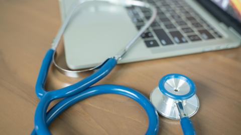 A stethoscope resting against an open laptop.