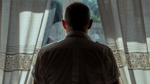 Shot from behind of a man looking out a window