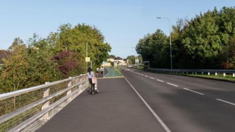 A view up a road from a bridge. There are trees either side of the road. In the distance is a green bike lane. A woman is walking with a pram in the distance.