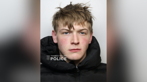 A mugshot of a young man in a black hoodie with a Thames Valley Police logo in the bottom left corner