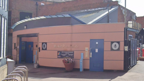 A toilet block building with flowers outside