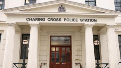 The words Charing Cross Police station are above the doorway with a coat of arms above and white classical-style columns on either side.
