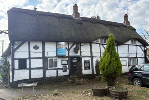 An derelict pub with a black and white outward appearance sits unoccupied