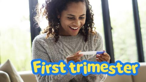 A woman smiles looking at her pregnancy test.