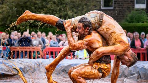 Two men wrestling in giant gravy pool