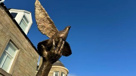 The bronze statue in front of a blue sky