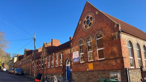 Hotwells Primary School in Hotwells, Bristol. It is a red brick building with lots of windows on it.