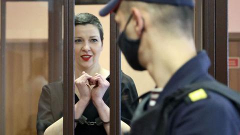 Maria Kolesnikova, the last remaining protest leader still in Belarus, gestures making a heart shape inside the defendants' cage during her verdict hearing on charges of undermining national security, conspiring to seize power and creating an extremist group, on September 6, 2021 in Minsk