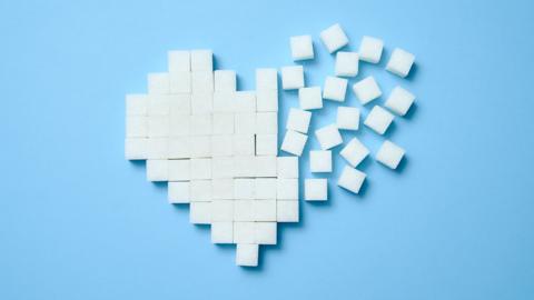 Sugar cubes arranged into a heart shape on a light blue background