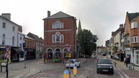The centre of Market Harborough with a mix of red brick and white-walled buildings on either side of the road