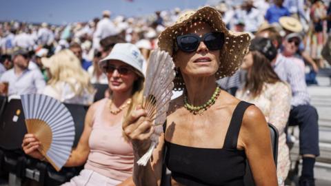 Spectators use fans to cool down at the Queen's Club Championships tennis tournament in London, Britain, 19 June 2025