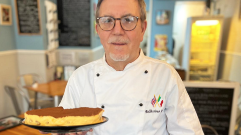 Giovanni Scidetta holds a plate of tiramisu