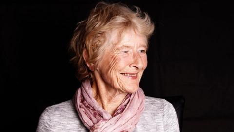 Joan smiling for a photograph taken by her daughter.