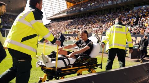 Xavi Simons being wheeled down a touchline on a stretcher