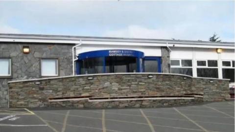 The exterior Ramsey District Cottage Hospital, the entrance is blue, and there is a stone ramp to the entrance.