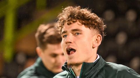 Isaac Moore head shot as he warms up bevfore a game in green Forest Green Rovers tracksuit