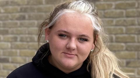 A young woman with long hair that is shades of light and darker blonde. 