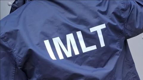 The back of a jacket with the initials IMLT on 