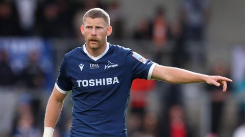 Rob du Preez holds his arm out and points while standing on the pitch during a match