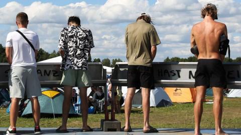 Men stand at urinals at a festival
