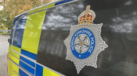 Image of North Yorkshire Police logo on blacked out window of Police van.