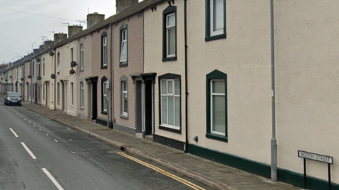 A street view of the terraced homes of Bolton Street. They are cream and beige coloured properties.