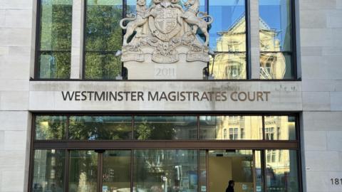 The front of Westminster Magistrates Court. The reception can just about be seen through the front entrance which is made up of glass doors and windows.