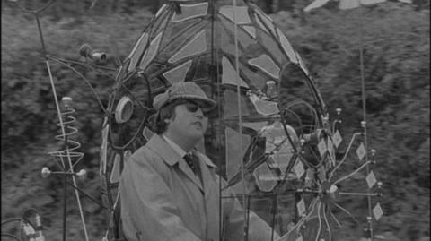 Black and white image of reporter sitting upon a lunar bike